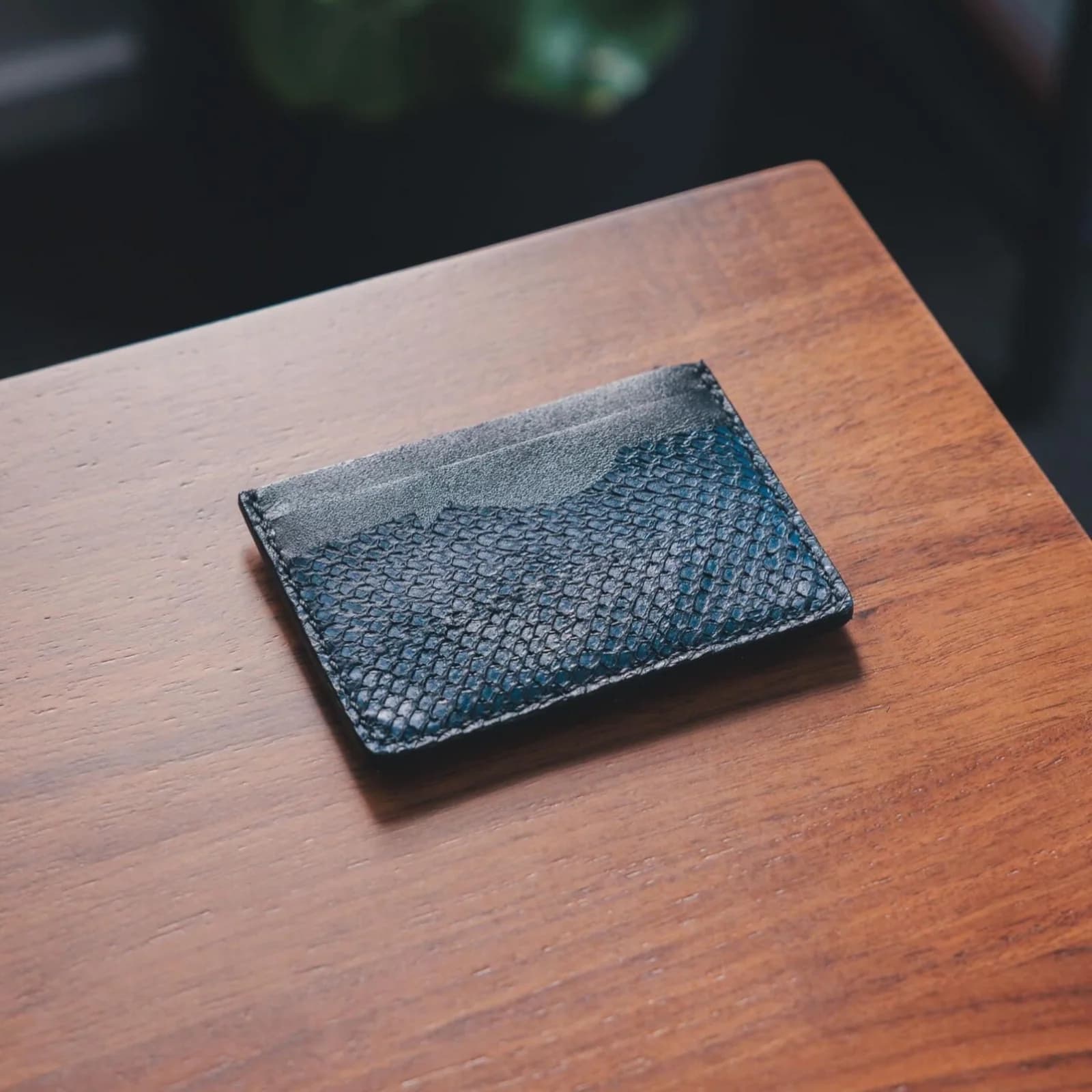 A dark blue fish leather card wallet on a wooden table